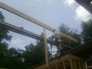 Carpenter setting a ridge beam over a new addition frame — Ice Dam Removal by Roofing Brothers in Burlison