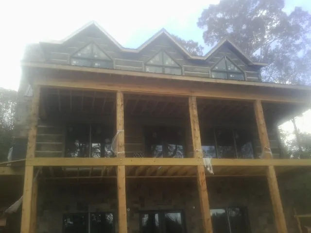 Dormers and porch framing on a large log home under construction — Roof Coating work by our crew in Burlison