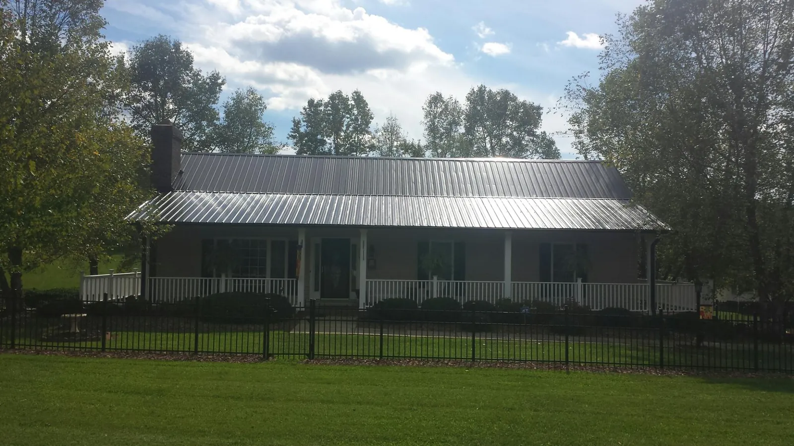 Gray metal roof on a brick ranch with a full width front porch in Burlison