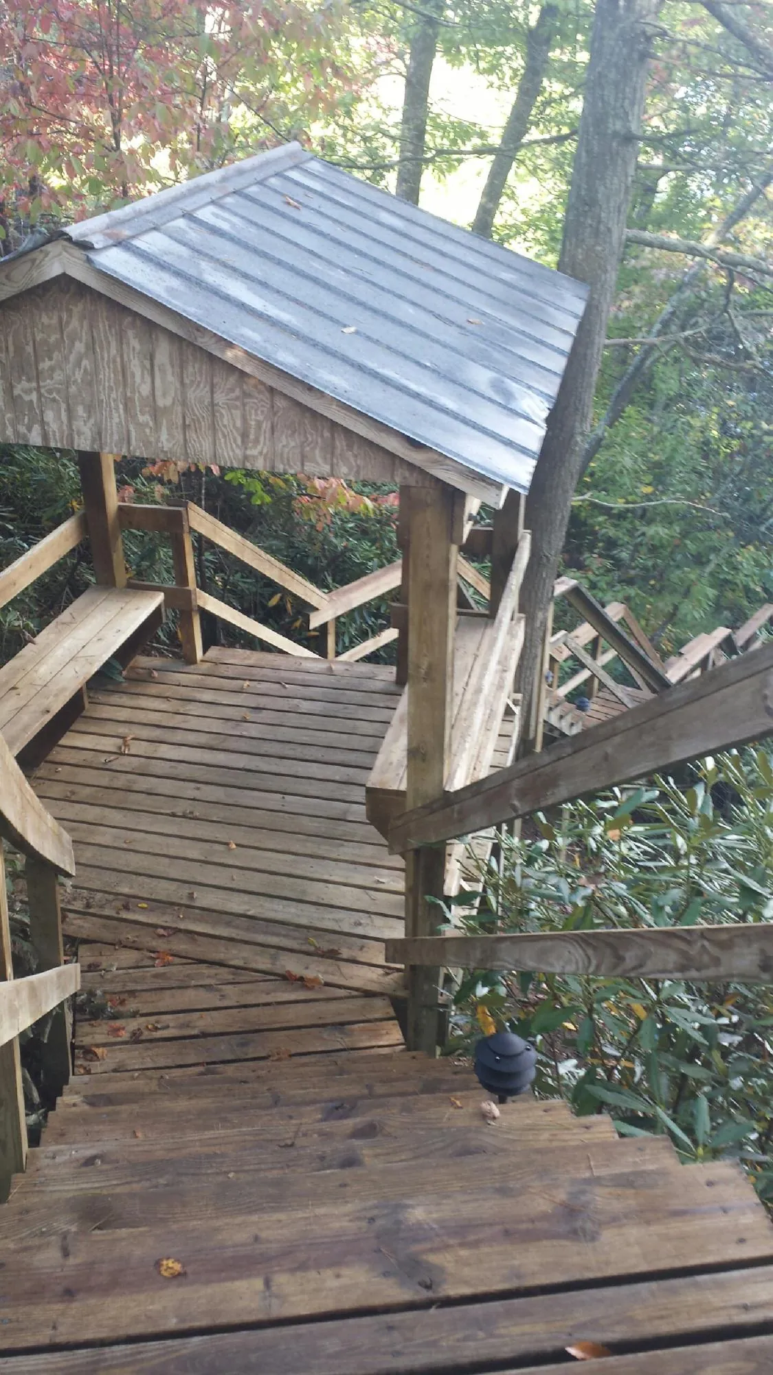 Metal roofed shelter over wooden steps on a wooded walkway — Skylight Repair & Installation work by our crew in Burlison