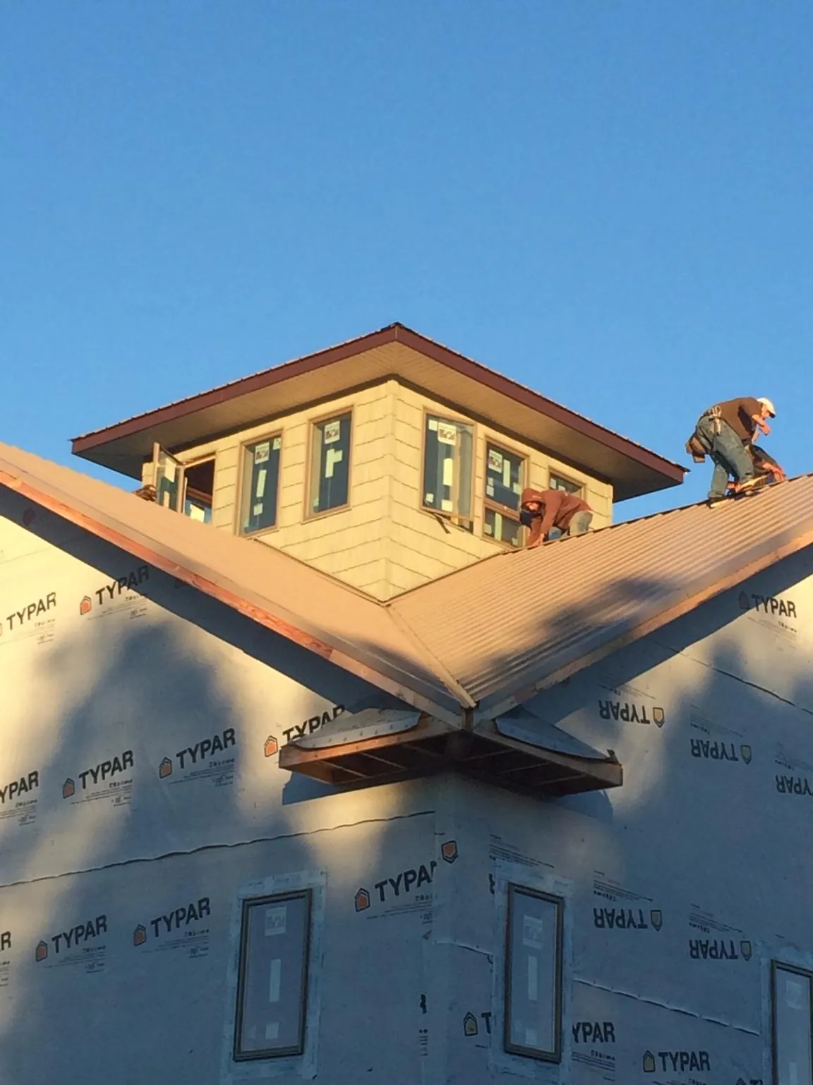 Roofers working around a rooftop cupola on a new metal roof at sunset — Roof Waterproofing in Burlison by Roofing Brothers
